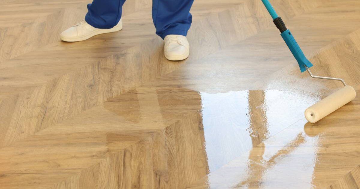 Eine Person ölt einen echten Holzboden mit einer Rolle